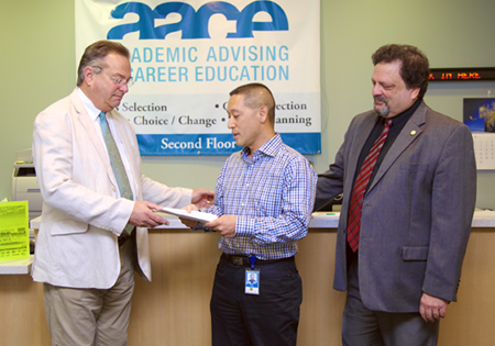 Scott Louie handing a check to Larry Bliss of the CSUEB career center.